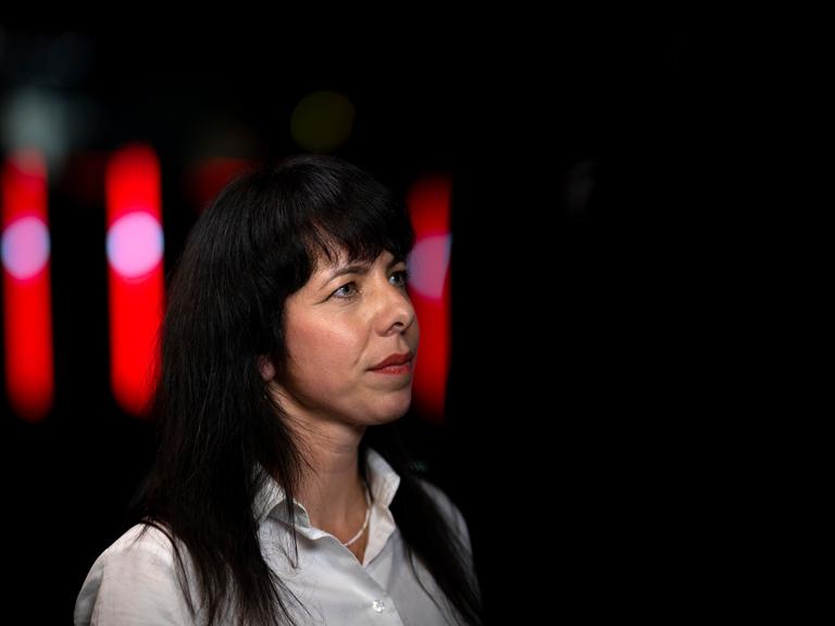 Elif Eralp , Spitzenkandidatin der Partei Die Linke in Berlin, ist bis zu den Schultern abgebildet. Sie trägt eine weiße Bluse, die schwarzen langen Haare offen und roten Lippenstift. Sie schaut an der Kamera vorbei. Elif Eralp , Spitzenkandidatin der Partei Die Linke in Berlin, ist bis zu den Schultern abgebildet. Sie trägt eine weiße Bluse, die schwarzen langen Haare offen und roten Lippenstift. Sie schaut an der Kamera vorbei.