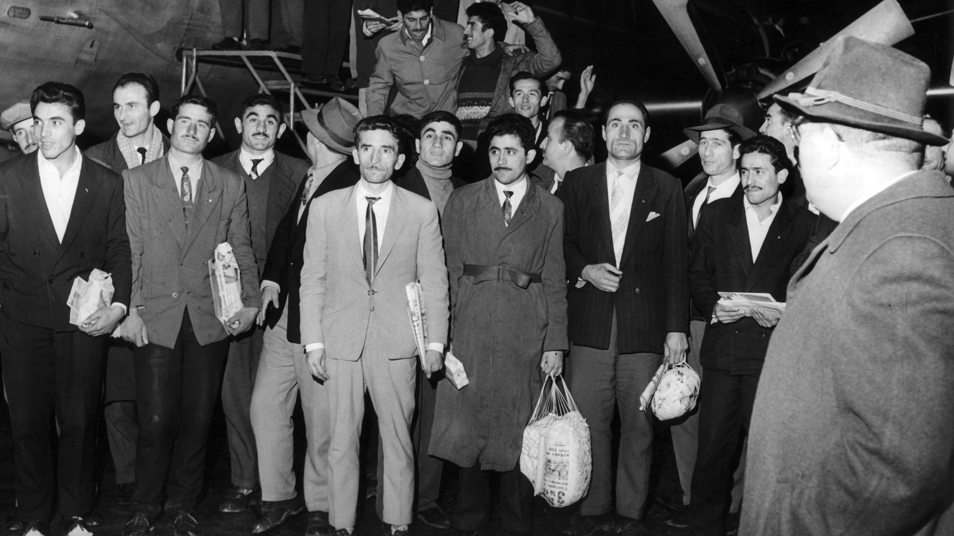 Historisches Schwarzweißfoto zahlreicher junger Männer, die aus einem Flugzeug steigen und sich davor für ein Gruppenfoto aufstellen. Historisches Schwarzweißfoto zahlreicher junger Männer, die aus einem Flugzeug steigen und sich davor für ein Gruppenfoto aufstellen.