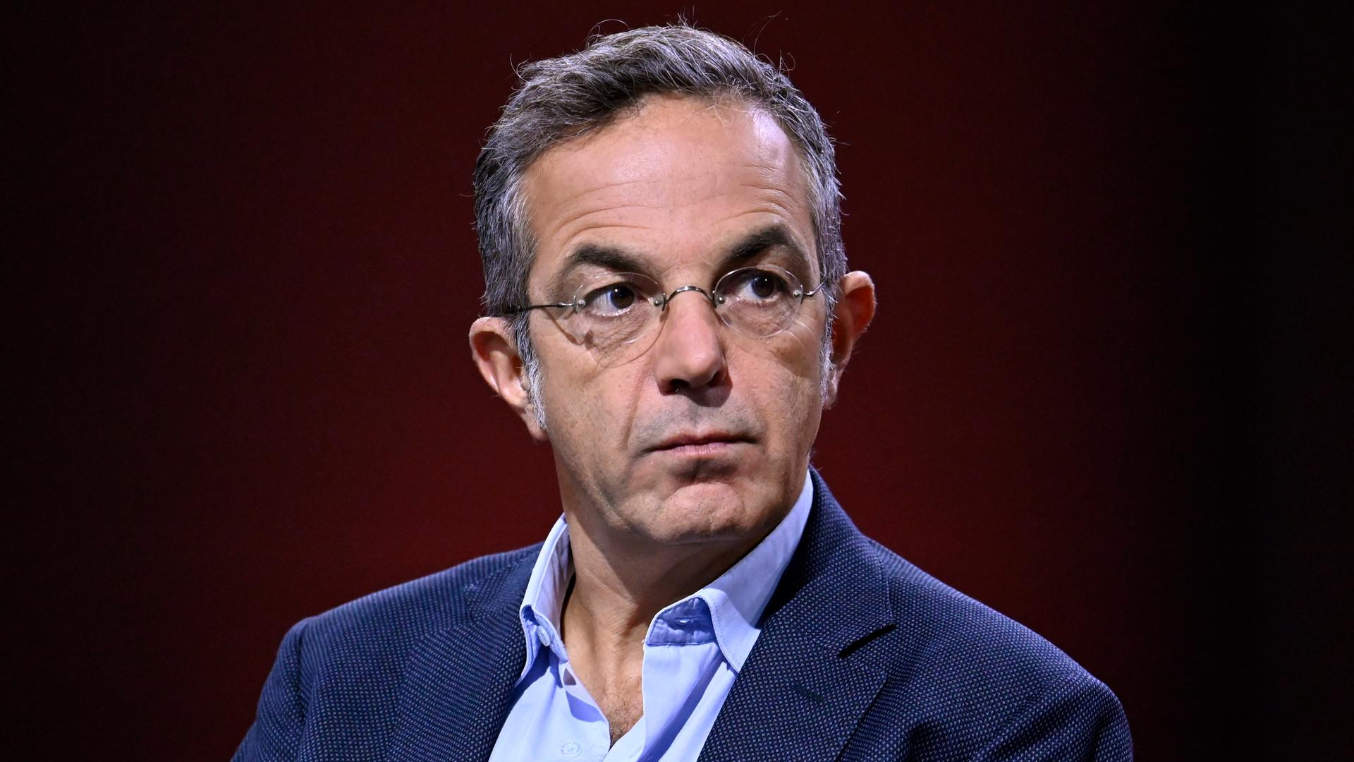 Schriftsteller Navid Kermani schaut ernst vor dunklem Hintergrund. 