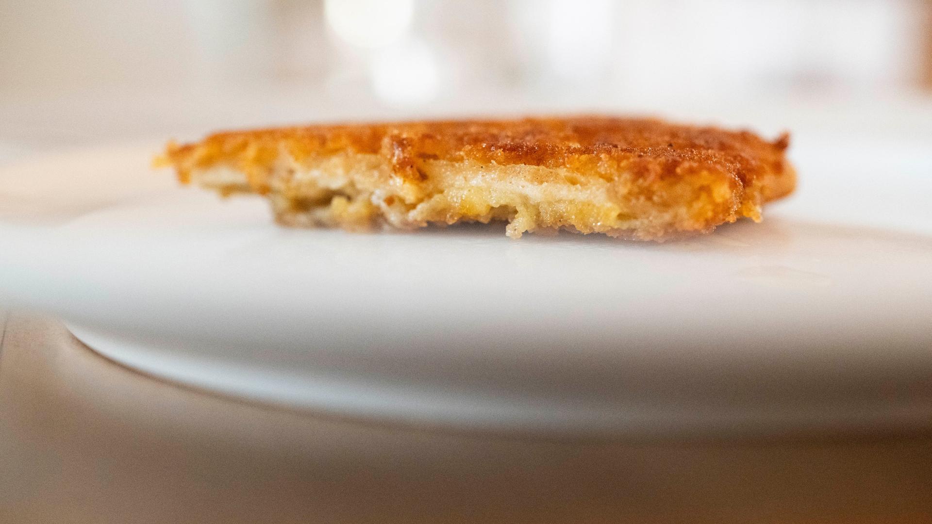 Ein veganes Schnitzel liegt auf einem Teller. Es sieht gut aus. Das Äußere ist offenbar goldfarben und knusprig, das Innere faserig und hell. Ein veganes Schnitzel liegt auf einem Teller. Es sieht gut aus. Das Äußere ist offenbar goldfarben und knusprig, das Innere faserig und hell.