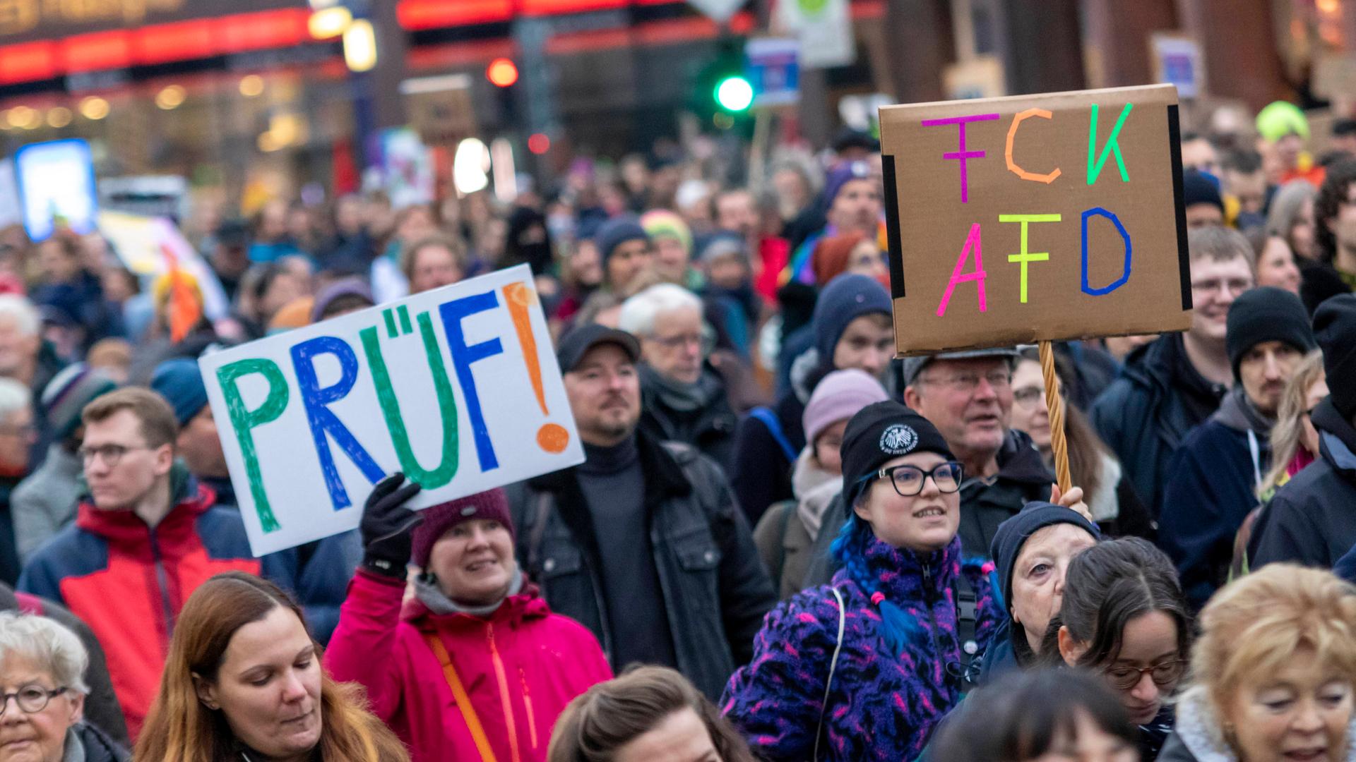 Eine Menschenmenge auf einer Demonstration in Hamburg. Eine Frau hält ein Schild mit der Aufschrift "Prüf" hoch. Eine andere Frau trägt ein Schild mit der Auschrift "FCK AfD".