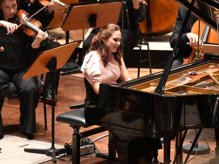 Blick auf die am Flügel sitzende und dabei strahlende Pianistin während ihres Auftrittes mit dem Mahler Chamber Orchestra.