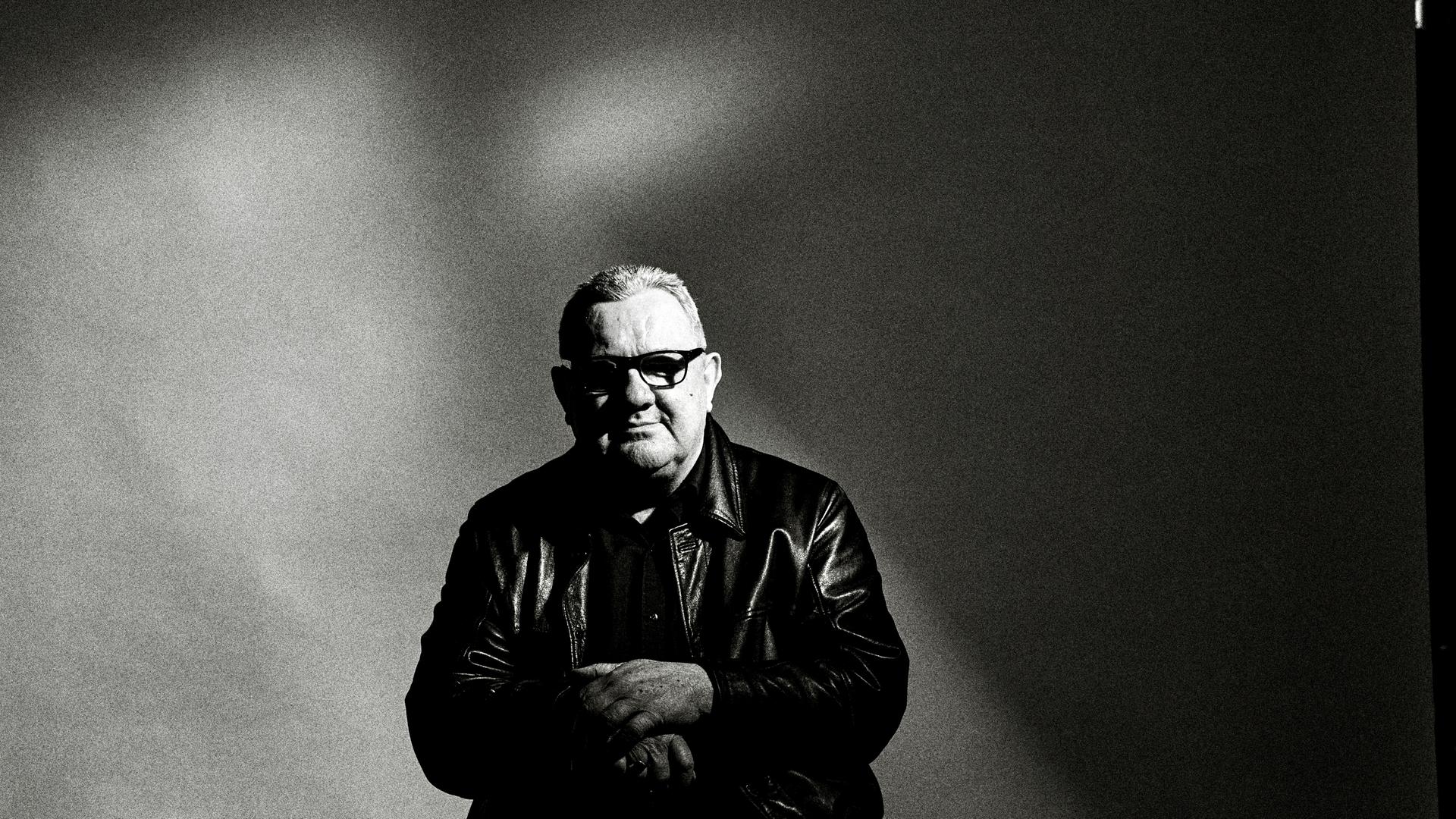 Das Schwarz-Weiß-Bild zeigt den Musiker Dave Ball. Er trägt eine Sonnenbrille und sitzt vor einem dunklen Hintergrund. Das Schwarz-Weiß-Bild zeigt den Musiker Dave Ball. Er trägt eine Sonnenbrille und sitzt vor einem dunklen Hintergrund.