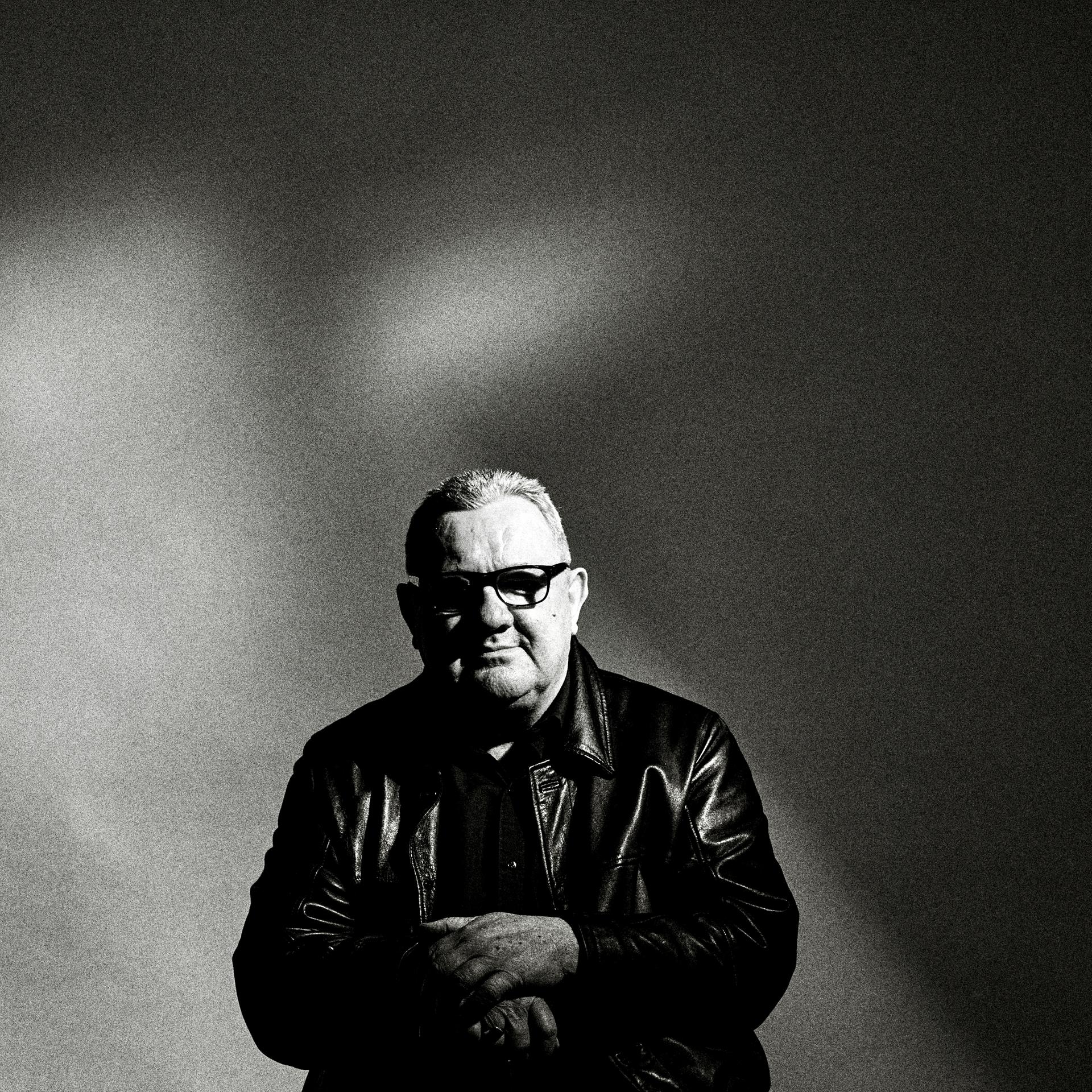 Das Schwarz-Weiß-Bild zeigt den Musiker Dave Ball. Er trägt eine Sonnenbrille und sitzt vor einem dunklen Hintergrund. Das Schwarz-Weiß-Bild zeigt den Musiker Dave Ball. Er trägt eine Sonnenbrille und sitzt vor einem dunklen Hintergrund.