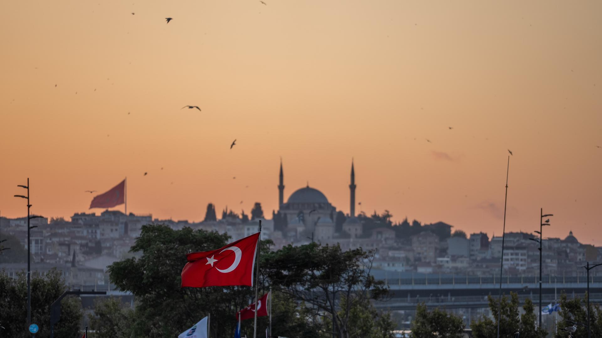 Die Yavuz-Sultan-Selim-Moschee in Istanbul und eine türkische Flagge bei Sonnenuntergang Die Yavuz-Sultan-Selim-Moschee in Istanbul und eine türkische Flagge bei Sonnenuntergang
