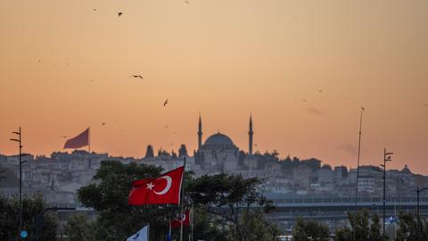 Die Yavuz-Sultan-Selim-Moschee in Istanbul und eine türkische Flagge bei Sonnenuntergang
