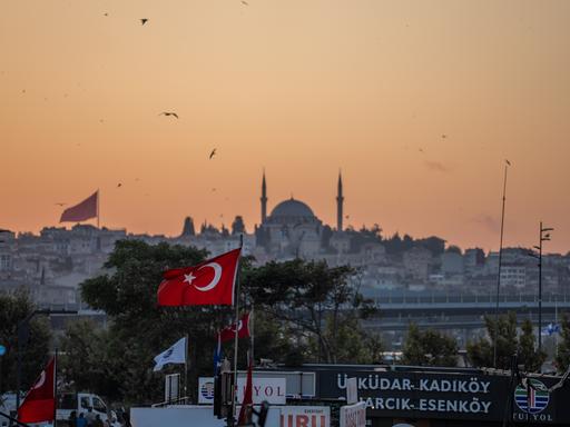 Die Yavuz-Sultan-Selim-Moschee in Istanbul und eine türkische Flagge bei Sonnenuntergang