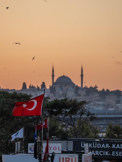 Die Yavuz-Sultan-Selim-Moschee in Istanbul und eine türkische Flagge bei Sonnenuntergang