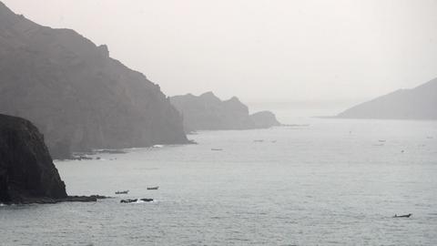 Links und rechts hohe Felsen, auf dem Wasser einige Fischerboote.