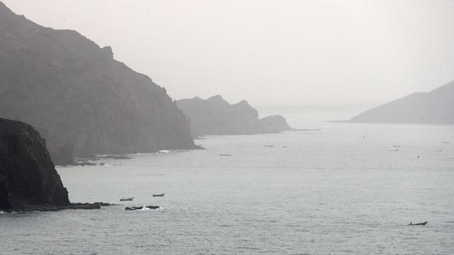Links und rechts hohe Felsen, auf dem Wasser einige Fischerboote.