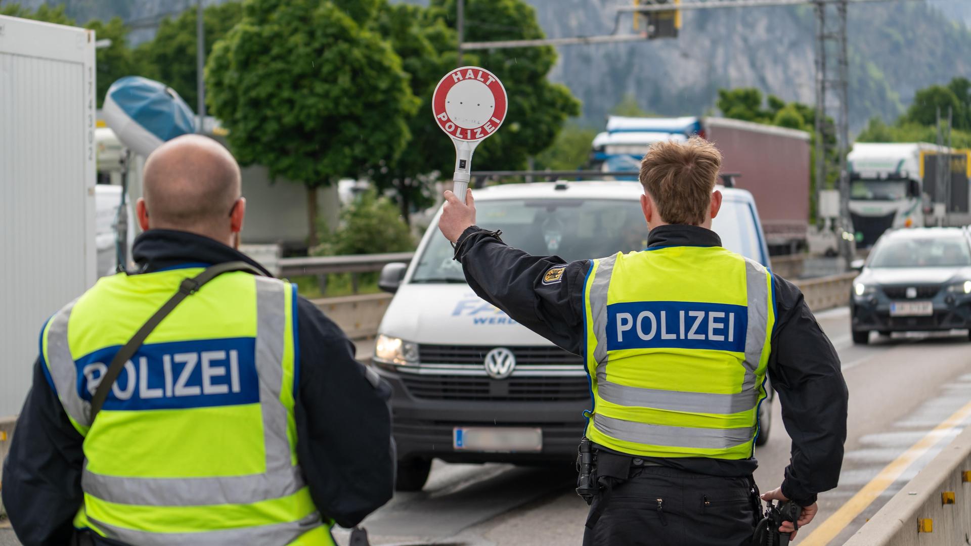 Ein Polizist stoppt ein Fahrzeug auf der Autobahn mit einer Polizeikelle mit der Aufschrift: "Halt Polizei". Neben ihm steht ein anderer Polizist.
Ein Polizist stoppt ein Fahrzeug auf der Autobahn mit einer Polizeikelle mit der Aufschrift: "Halt Polizei". Neben ihm steht ein anderer Polizist.