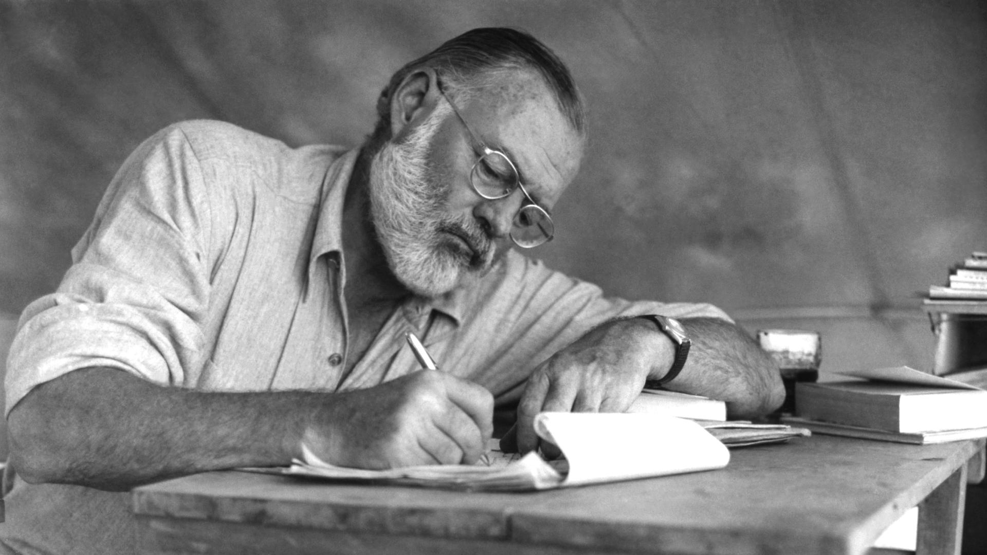 Der amerikanische Schriftsteller Ernest Hemingway (1899–1961) bei der Schreibarbeit an einem Klapptisch während einer Großwildjagd in Kenia, September 1952. Der amerikanische Schriftsteller Ernest Hemingway (1899–1961) bei der Schreibarbeit an einem Klapptisch während einer Großwildjagd in Kenia, September 1952.