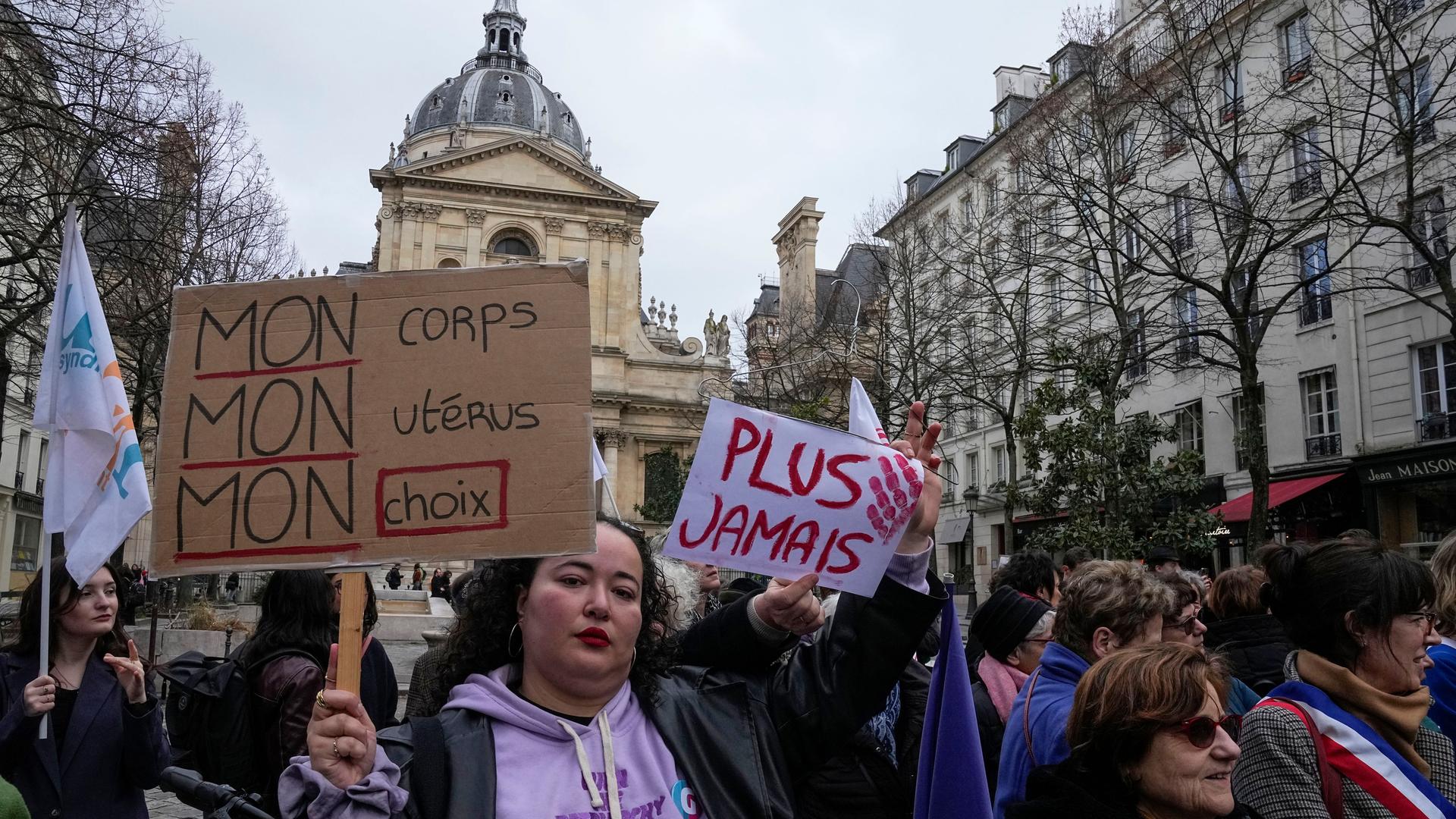 Eine Frau hält bei einer Demonstration ein Schild hoch. Auf dem Schild steht «Mein Körper, meine Gebärmutter, meine Entscheidung» und «Nie wieder»