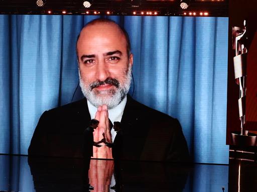 Aus dem Iran zugeschaltet: Misagh Zare bedankt sich für die Lola für die beste männliche Hauptrolle in dem Film "Die Saat des heiligen Feigenbaums" während der 75. Verleihung des Deutschen Filmpreises in Berlin