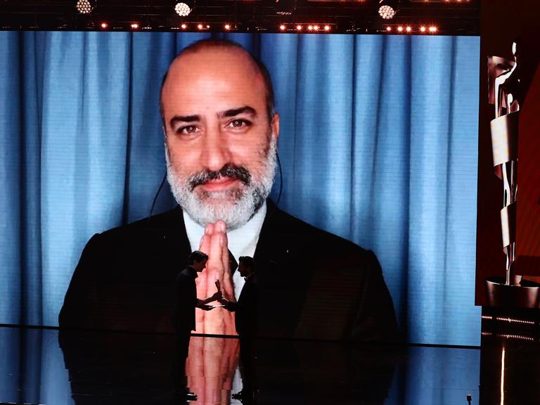 Aus dem Iran zugeschaltet: Misagh Zare bedankt sich für die Lola für die beste männliche Hauptrolle in dem Film "Die Saat des heiligen Feigenbaums" während der 75. Verleihung des Deutschen Filmpreises in Berlin