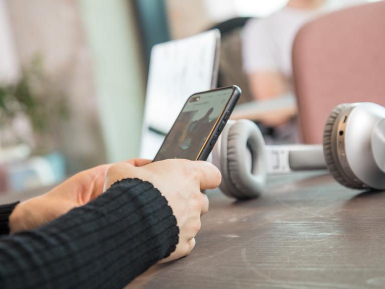 Eine Frau schaut in einem Coworking Space auf ihr Smartphone.