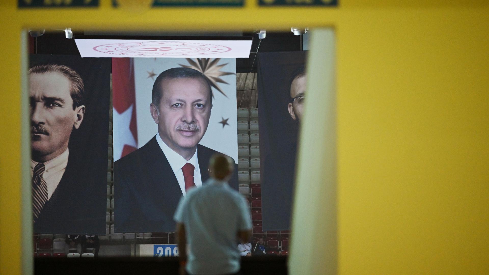 Bei einer Sportveranstaltung sind Transparente mit Bildern von Recep Tayyip Erdgan und Staatsgründer Mustafa Kemal Atatürk aufgehängt. Ein Mann steht davor. 