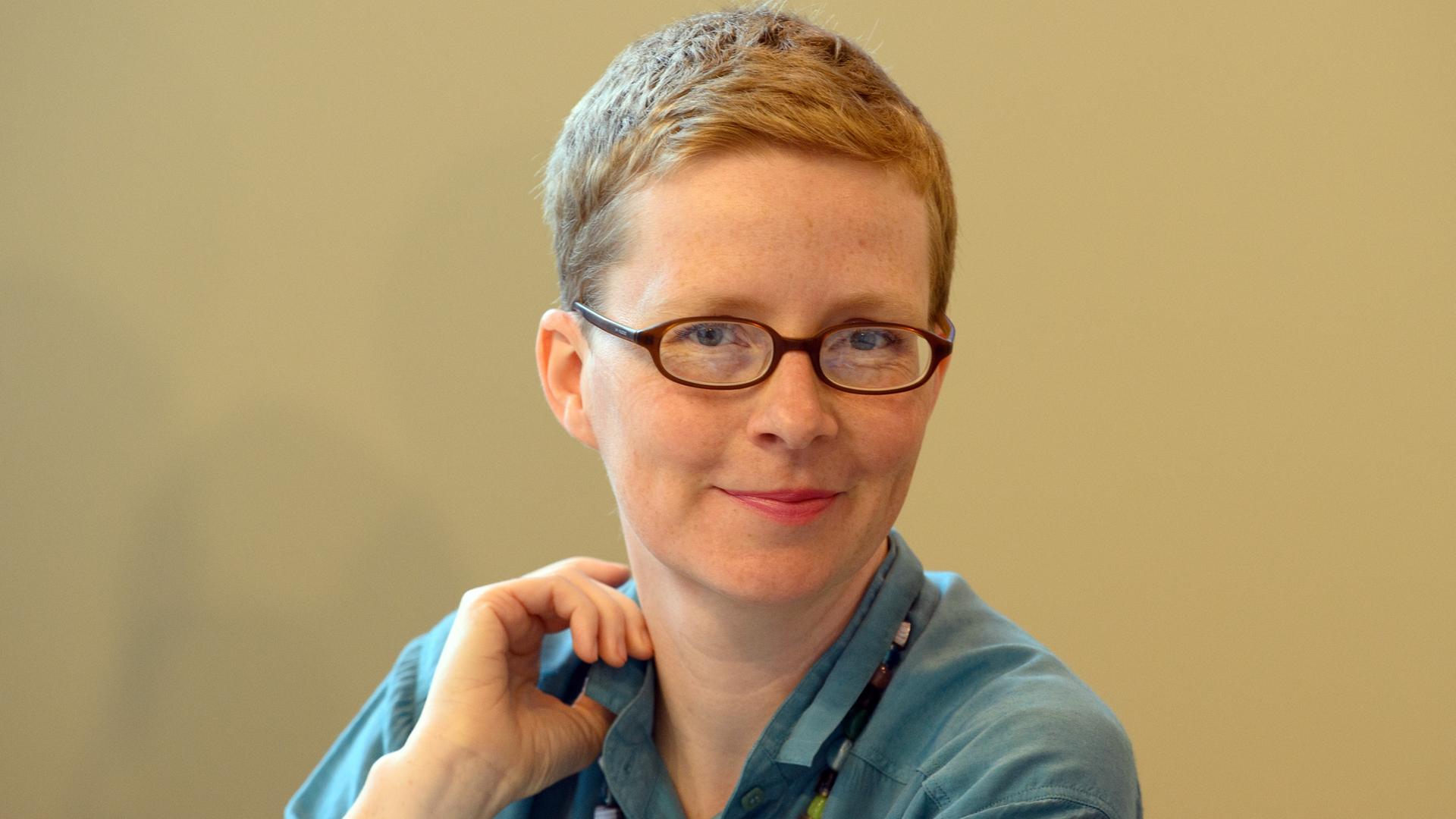Die Schriftstellerin Judith Zander lächelt mit Brille und kurzen Haaren in die Kamera.