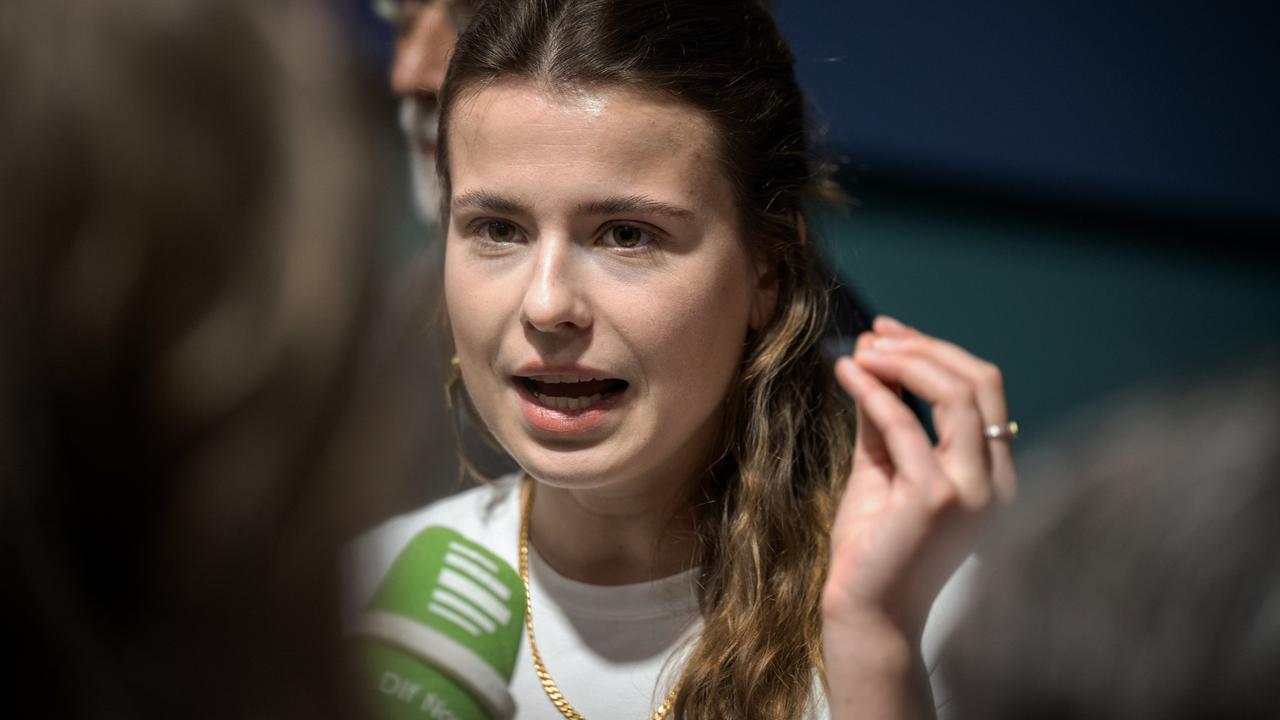 Eine Frau spricht mit erhobener linker Hand in ein Mikrofon.