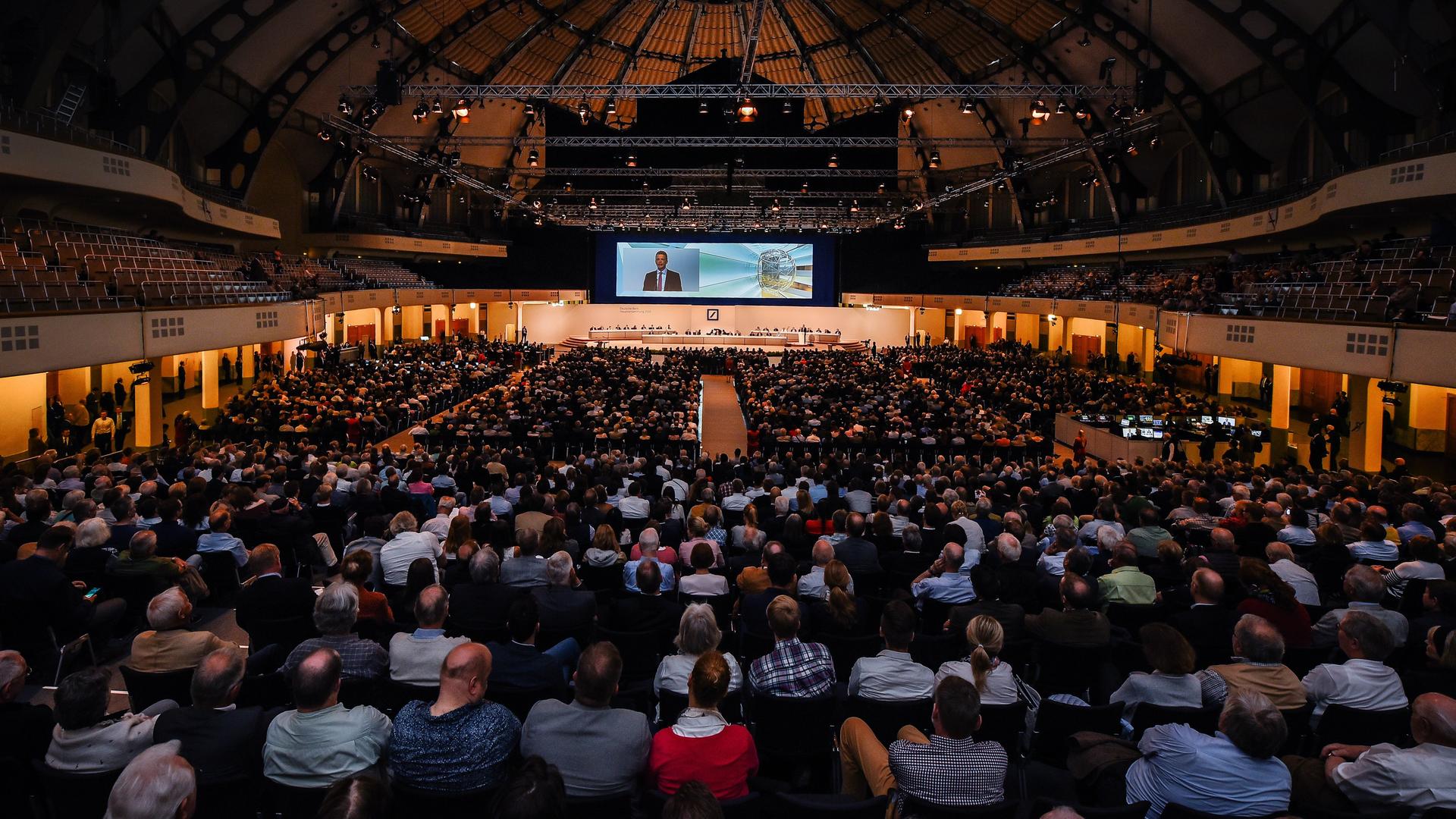 Sehr viele Aktionäre sitzen auf der Hauptversammlung der Deutschen Bank in Frankfurt am Main in einer großen Halle im Jahre 2018.