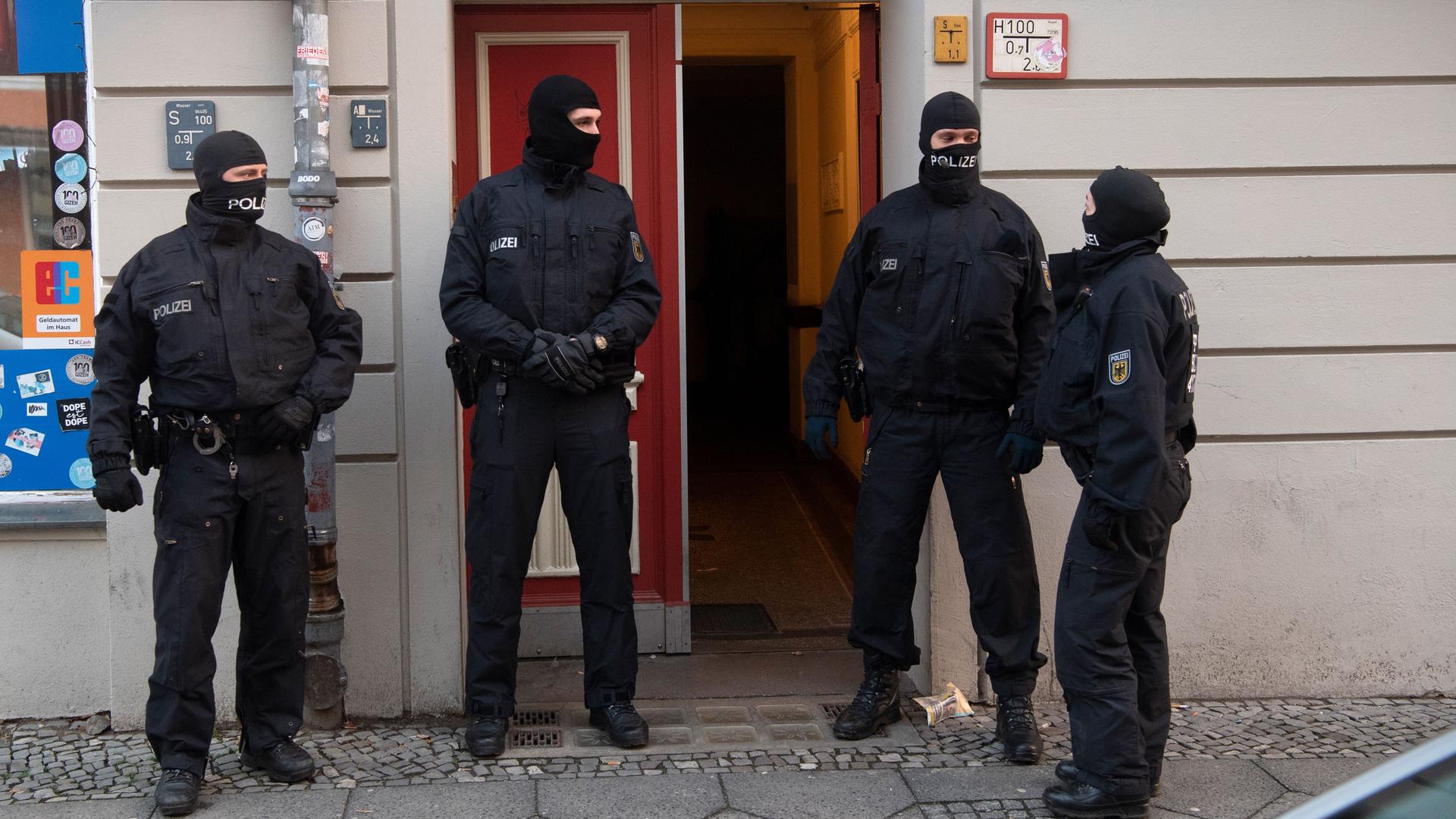 Berlin: Polizisten stehen bei einer Razzia an einer Eingangstür von einem Gebäude in Berlin. Mit einer großen Razzia ist die Polizei in Berlin und Sachsen-Anhalt gegen eine Bande mutmaßlicher Schleuser vorgegangen.