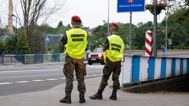  Polnische Grenz-Schützer stehen an der Grenze und beobachten den Verkehr. 