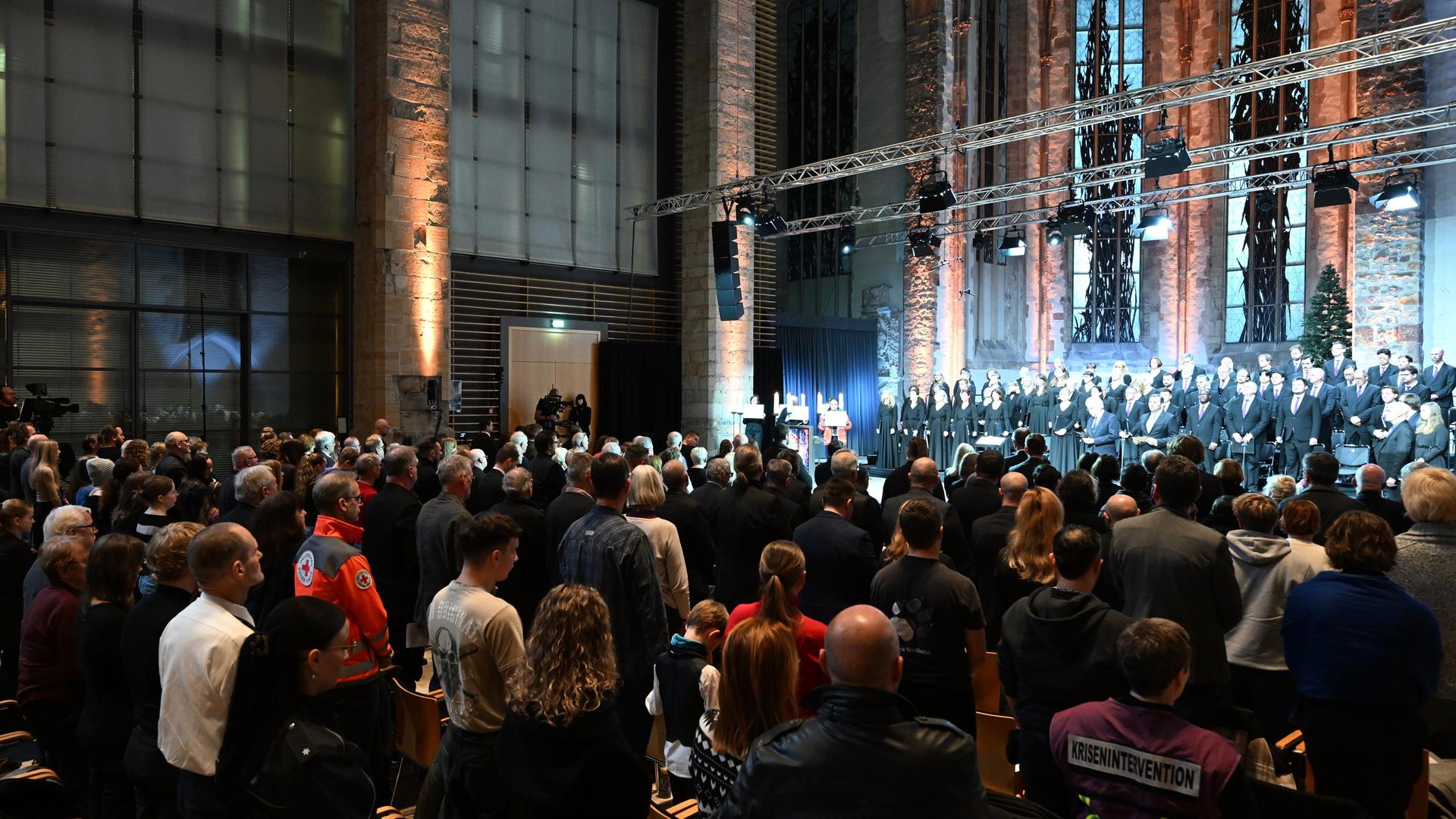 Betroffene und Hinterbliebene nehmen an der Gedenkveranstaltung teil. 