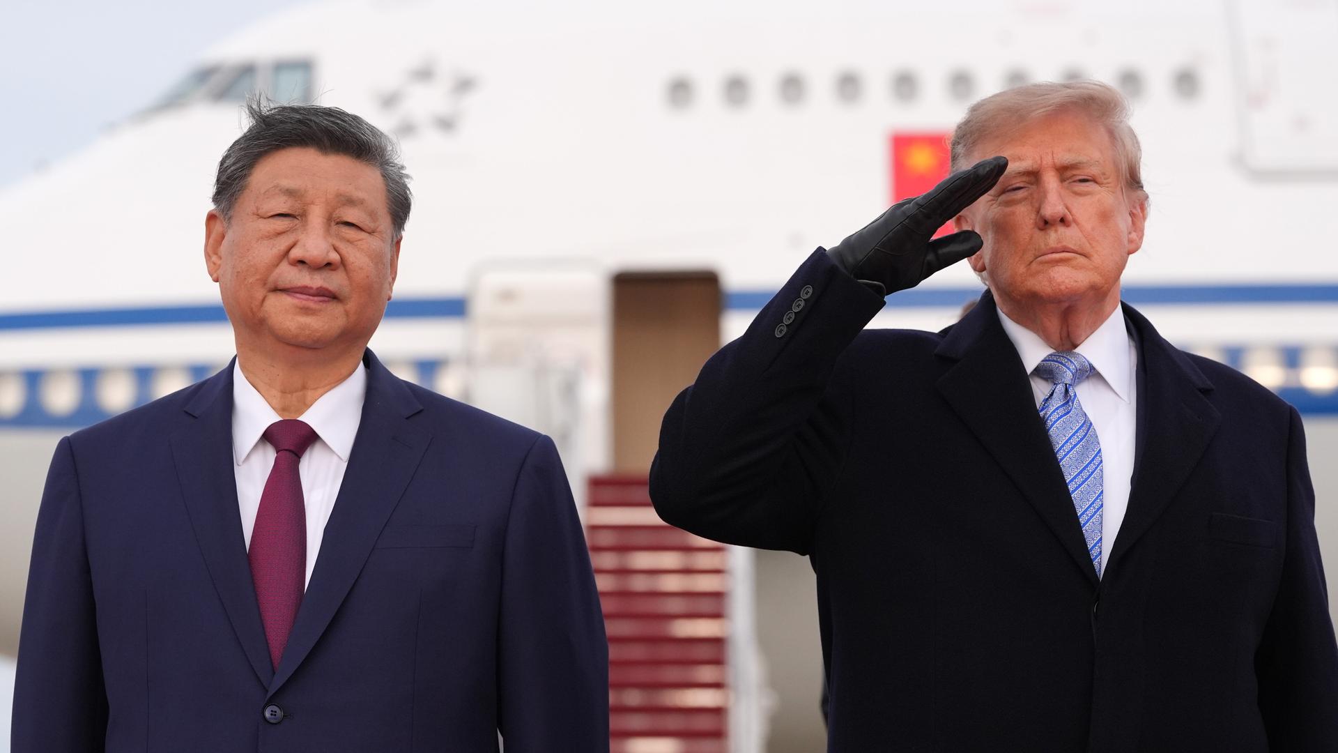 US-Präsident Trump und Chinas Staatschef Xi Jinping stehen nebeneinander. Trump salutiert.