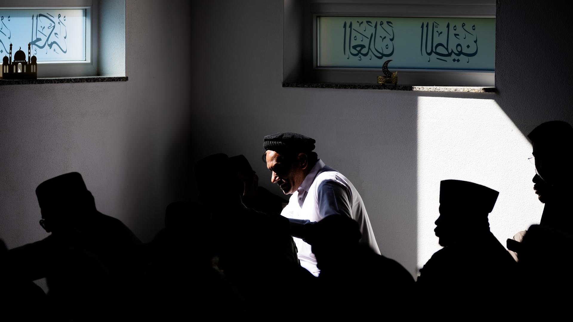 Gläubige im Gebetsraum der Khadija-Moschee Berlin. Sonnenlicht fällt durch ein Fenster mit arabischer Schrift in den Gebetsraum. Gläubige im Gebetsraum der Khadija-Moschee Berlin. Sonnenlicht fällt durch ein Fenster mit arabischer Schrift in den Gebetsraum.