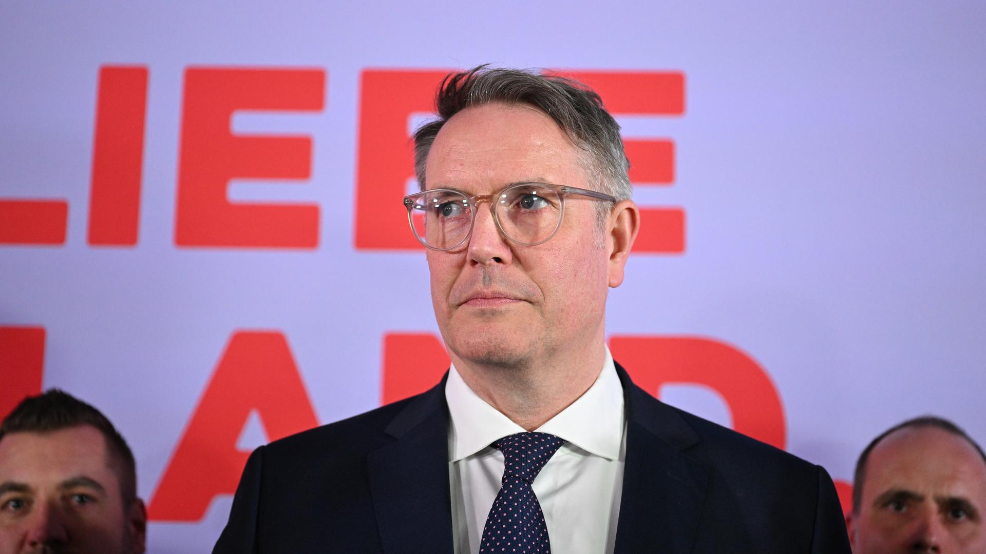 Zu sehen ist Alexander Schweitzer vor SPD-Parteianhängern. Nach seiner Wahlniederlage hat er einen ernsten und enttäuschten Gesichtsausdruck.