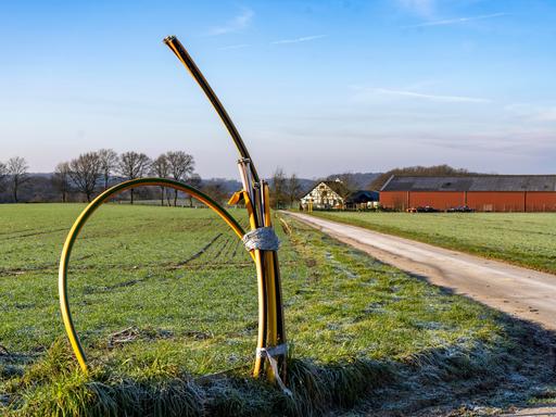 Leerrohre für Glasfaserkabel schauen an einem Feldweg aus dem Boden heraus.