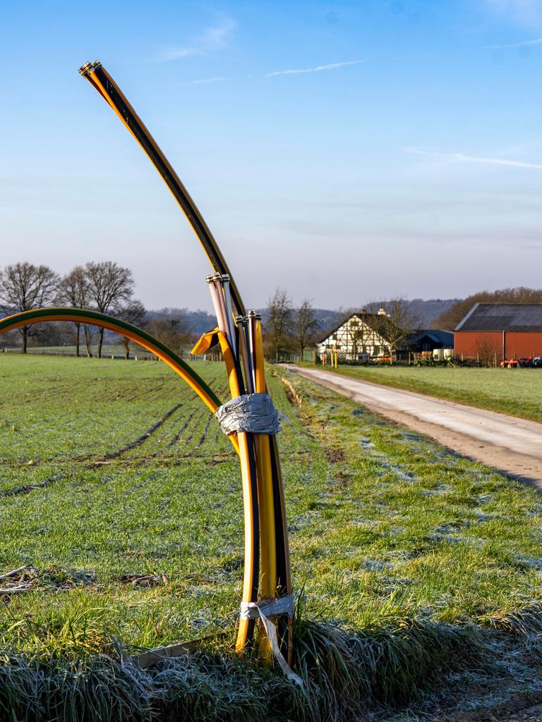 Leerrohre für Glasfaserkabel schauen an einem Feldweg aus dem Boden heraus.