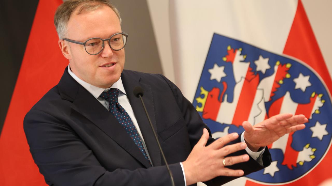 Thüringens Ministerpräsident Mario Voigt spricht vor der thüringischen Flagge 