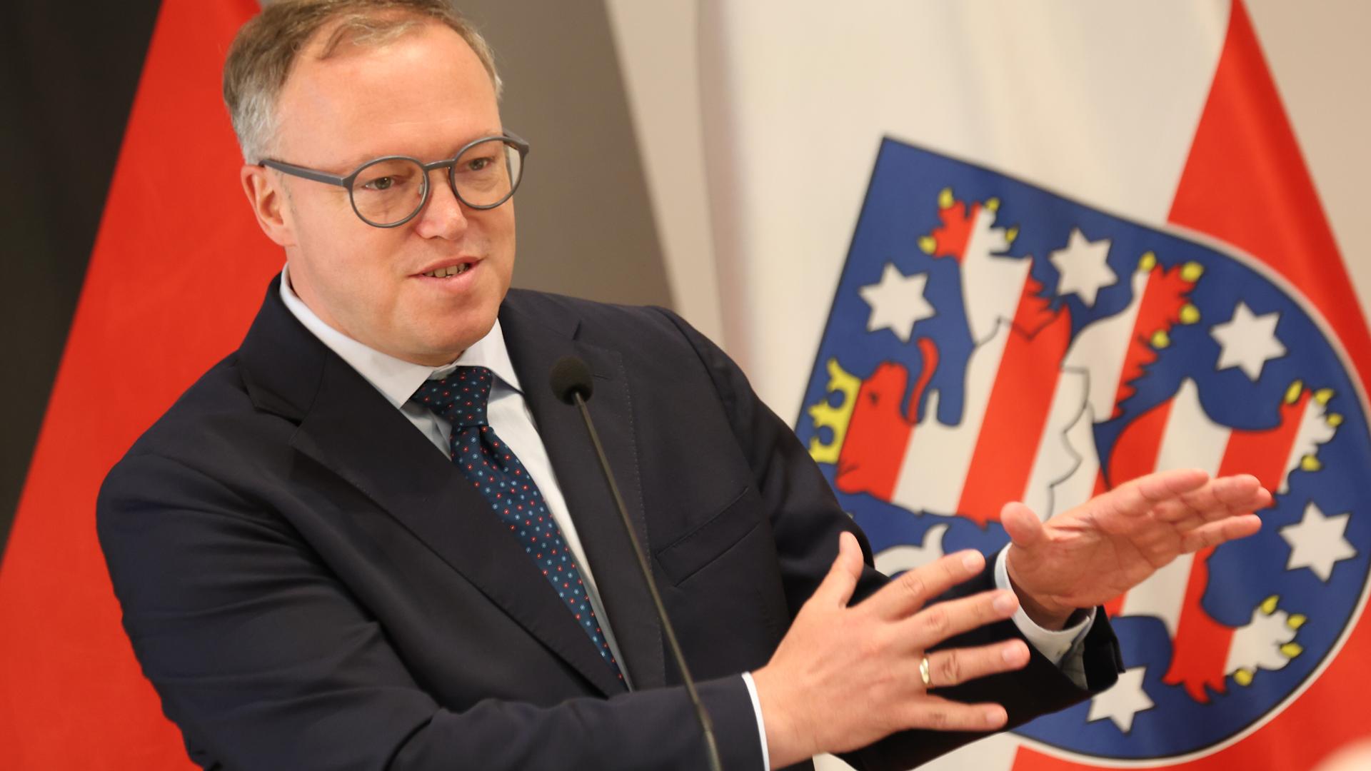 Thüringens Ministerpräsident Mario Voigt spricht vor der thüringischen Flagge 
