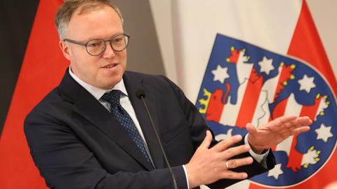 Thüringens Ministerpräsident Mario Voigt spricht vor der thüringischen Flagge 