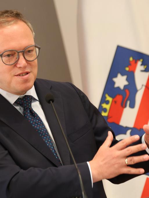 Thüringens Ministerpräsident Mario Voigt spricht vor der thüringischen Flagge 