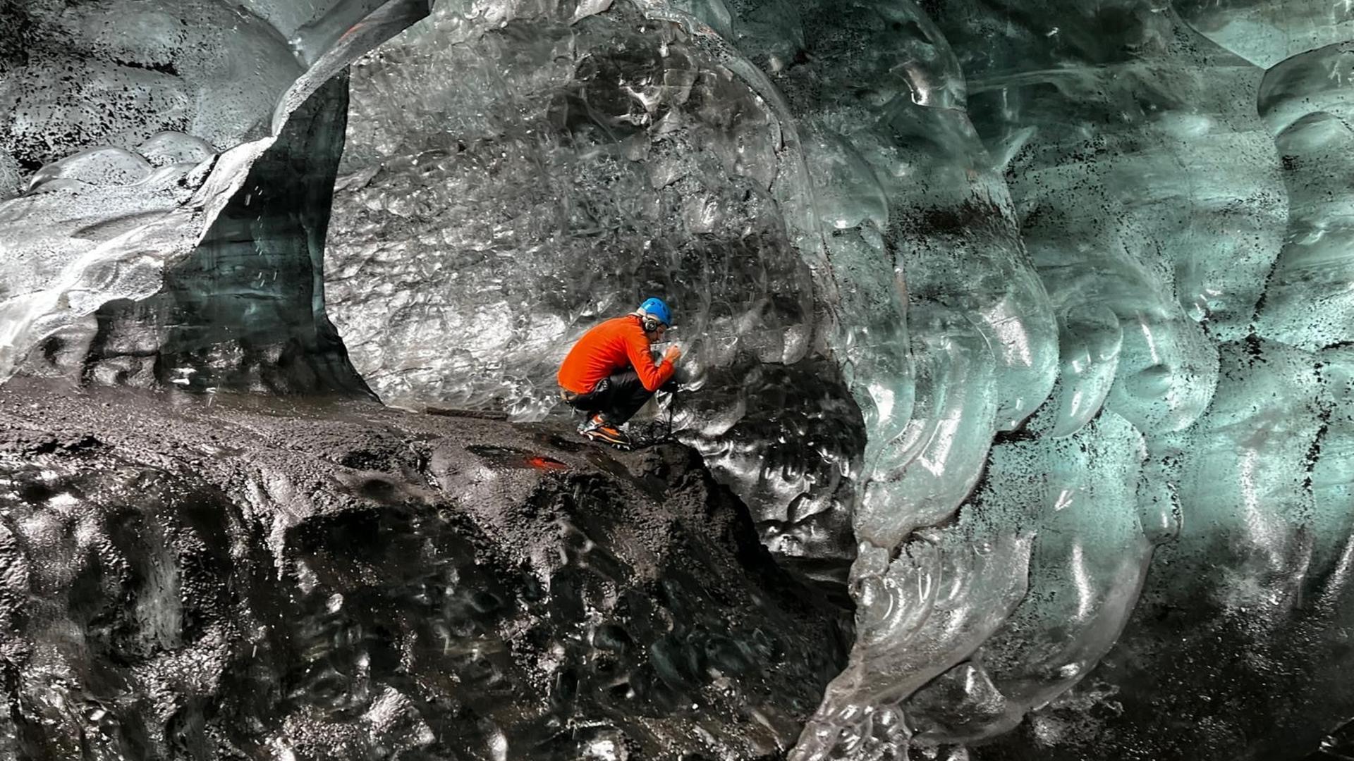 Ein Bergsteiger sitzt in einer Eishöhle