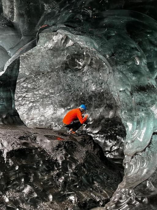 Ein Bergsteiger sitzt in einer Eishöhle