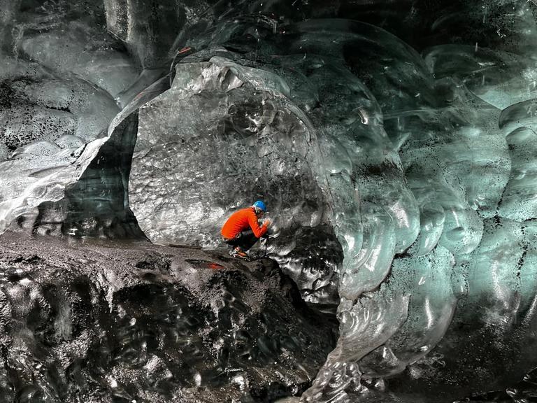 Ein Bergsteiger sitzt in einer Eishöhle