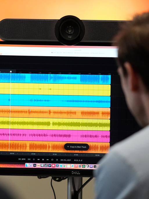 Auf einem Computerbildschirm werden während der Erstellung eines KI-Musikstücks bei SUNO die Wellenformen von Audiodateien verschiedener Instrumente angezeigt.