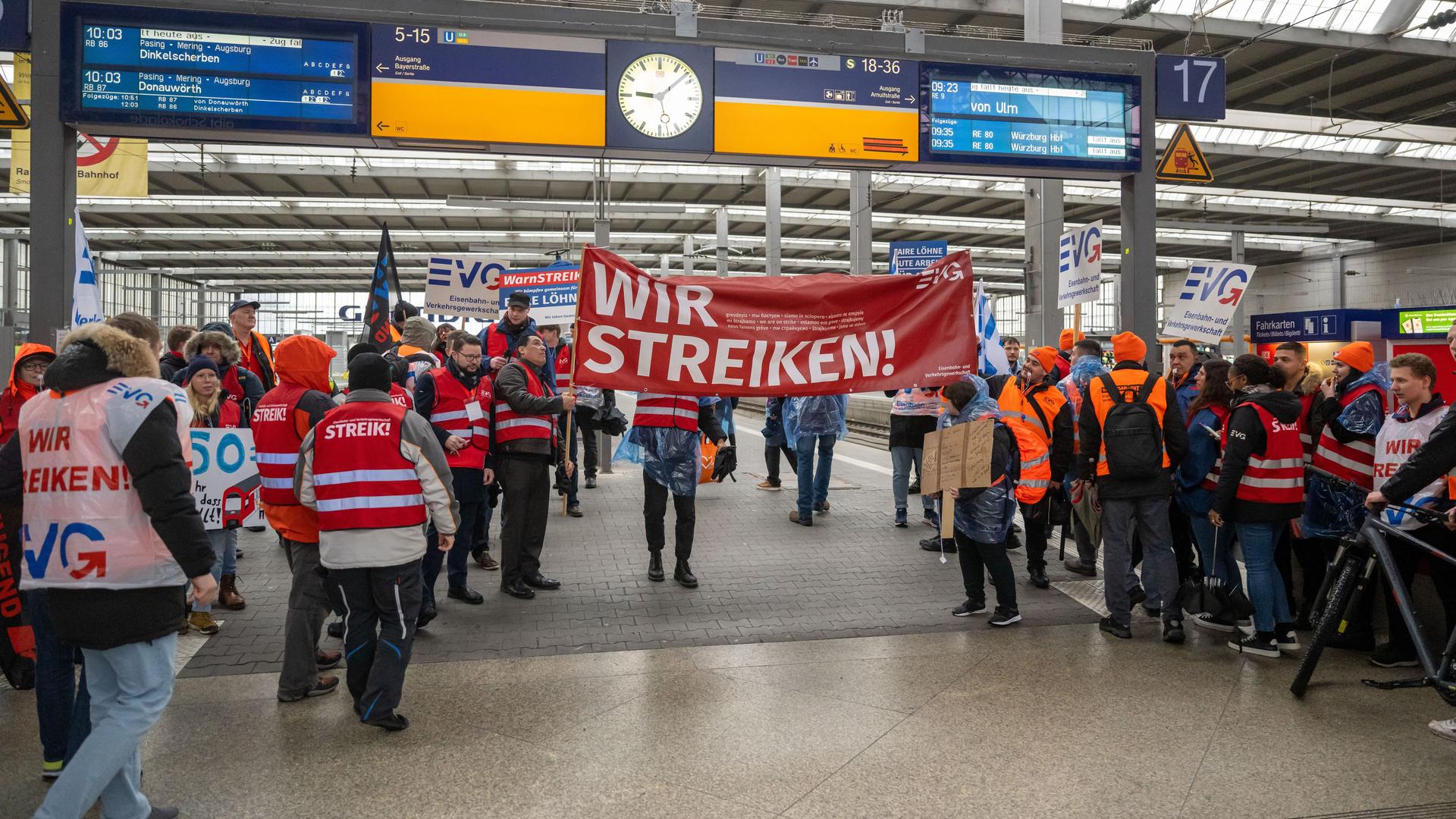 Mit Plakaten und Bannern ziehen Mitglieder der Menschen protestieren am Haupt-Bahnhof in der Stadt München und halten Plakate hoch. 