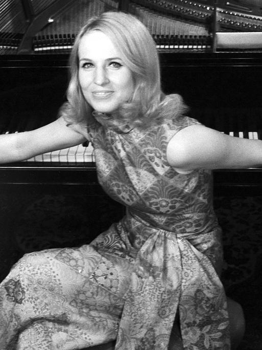 Schwarzweiß Bild der deutschen Pianistin und Hochschullehrerin Annerose Schmidt. Sie sitzt auf einem Hocker am Klavier und hat den Rücken zu dem Instrument gewandt und ihre Arme auf den Tasten ausgebreitet. Schwarzweiß Bild der deutschen Pianistin und Hochschullehrerin Annerose Schmidt. Sie sitzt auf einem Hocker am Klavier und hat den Rücken zu dem Instrument gewandt und ihre Arme auf den Tasten ausgebreitet.