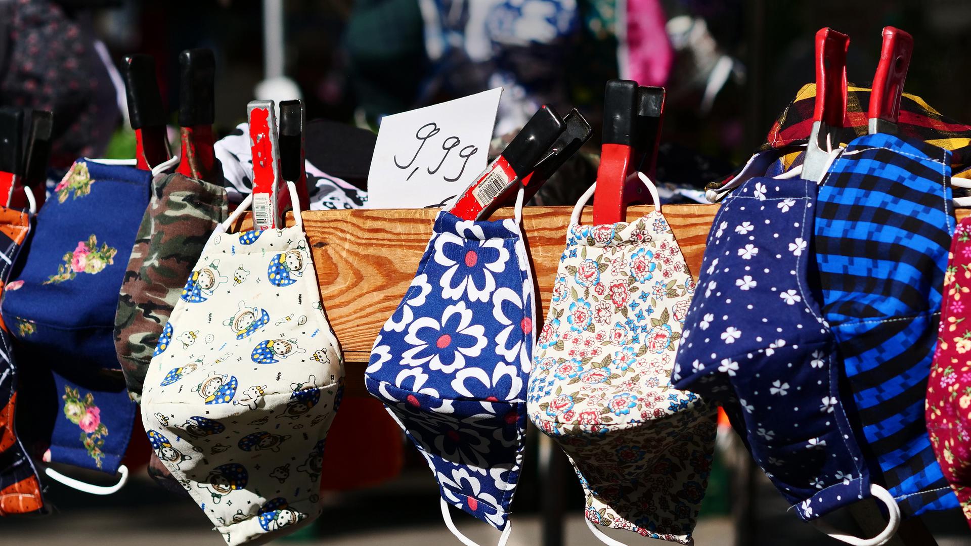 Mehrere bunte Stoffmasken an einem Marktstand