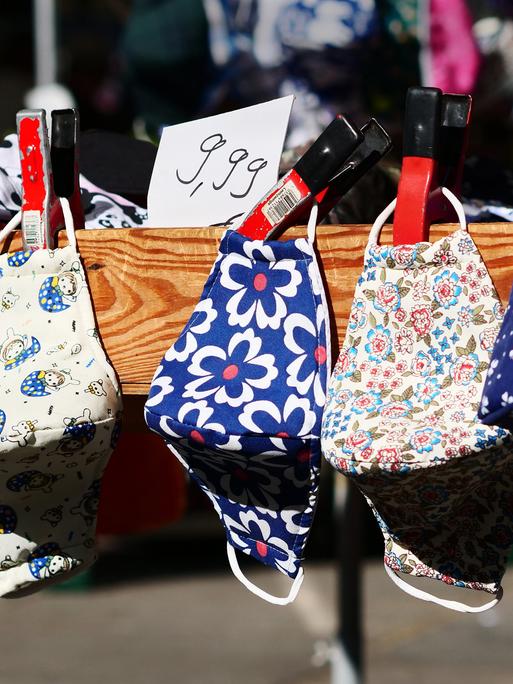 Mehrere bunte Stoffmasken an einem Marktstand