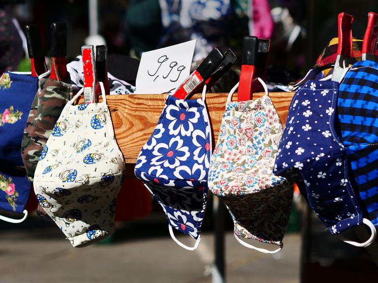 Mehrere bunte Stoffmasken an einem Marktstand