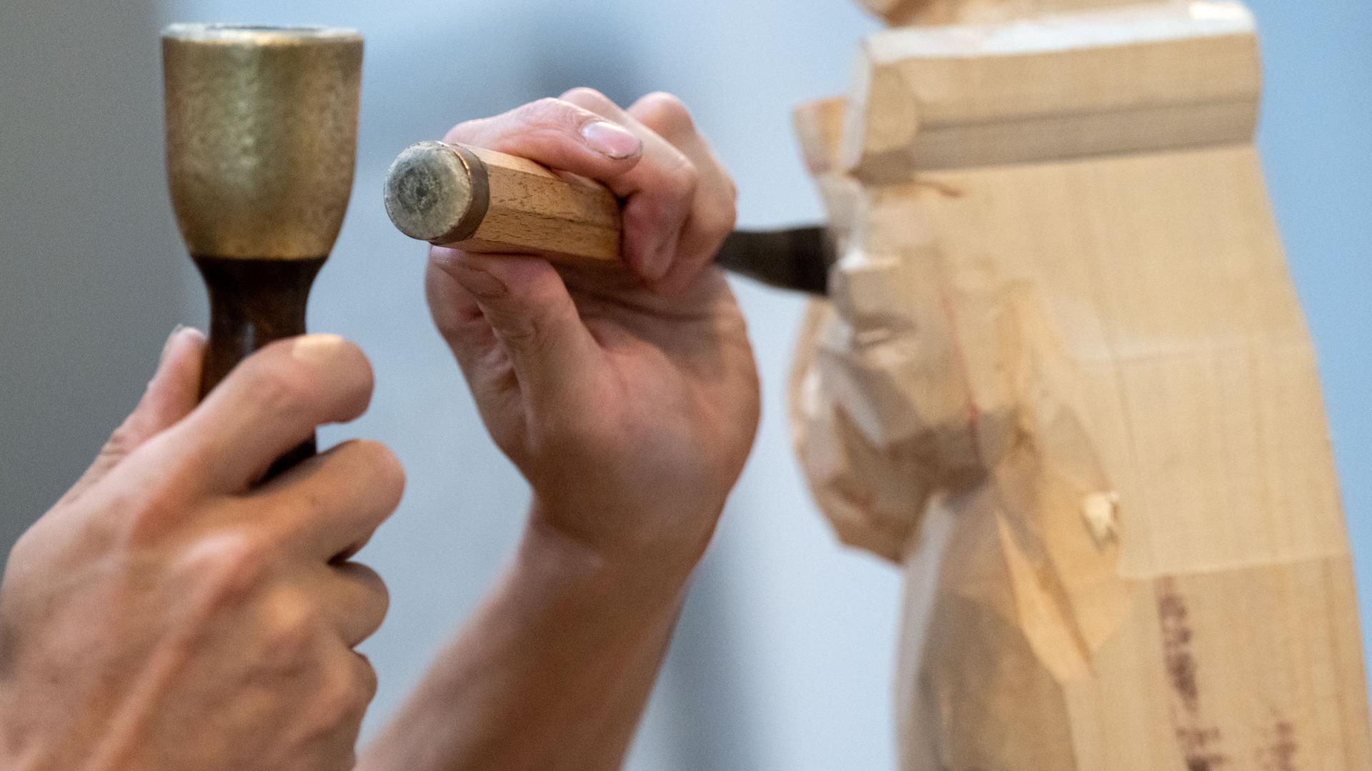 Ein Bildhauer arbeitet an einem Kunstwerk aus Holz. Ein Bildhauer arbeitet an einem Kunstwerk aus Holz.