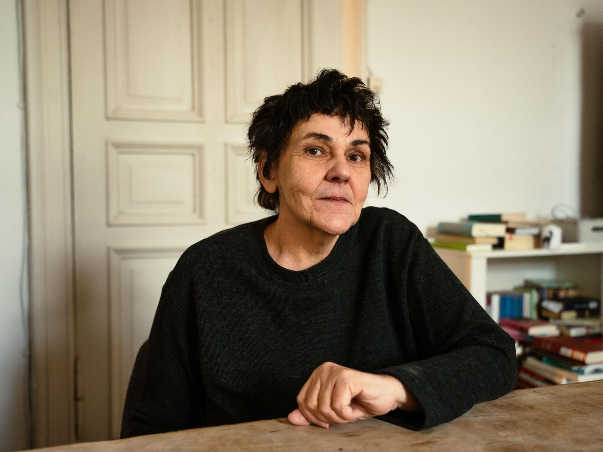 Christiane Rösinger sitzt an einem Tisch und schaut in die Kamera