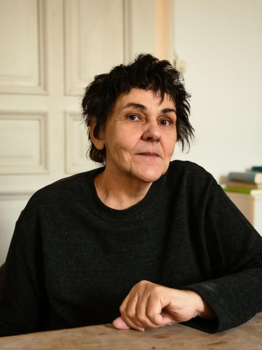 Christiane Rösinger sitzt an einem Tisch und schaut in die Kamera