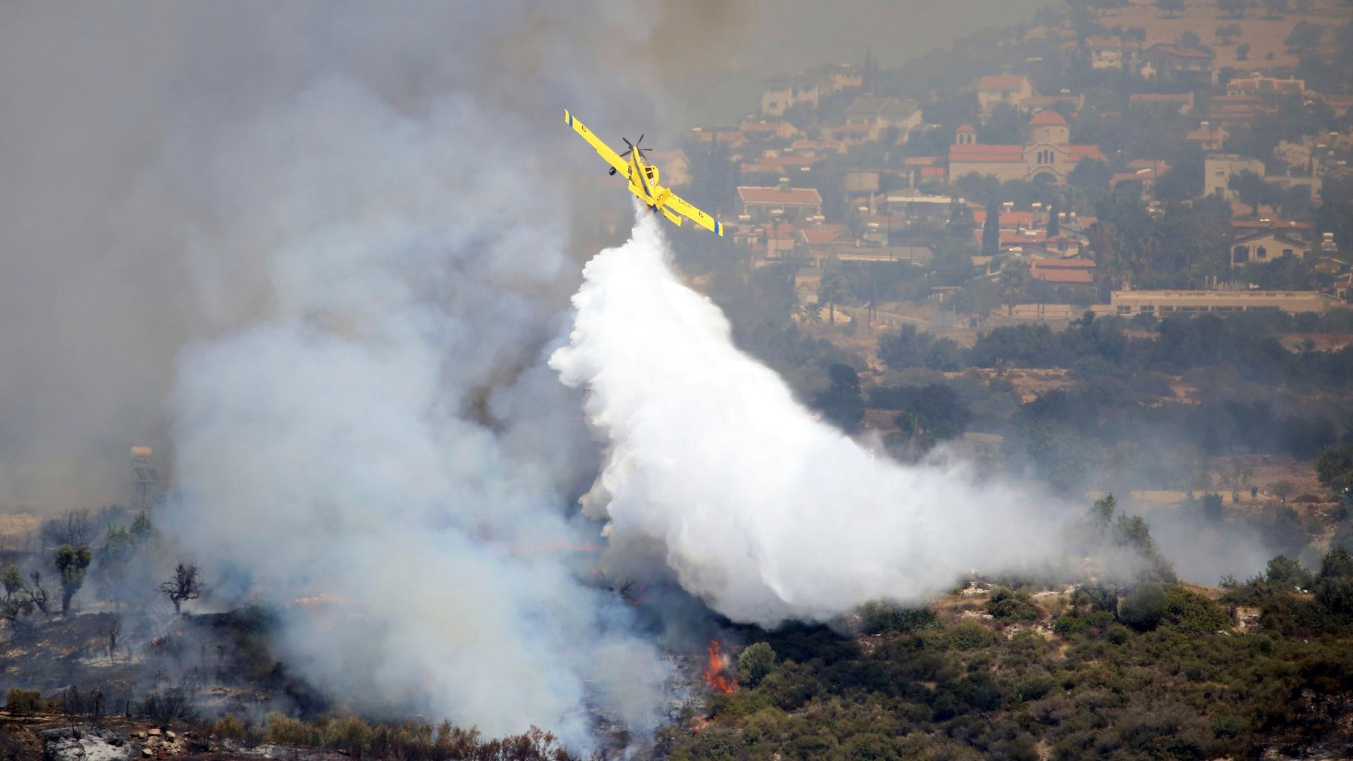 Zypern, Apesia: Ein Flugzeug wirft Löschwasser über einem Feuer in Apesia, einem halbgebirgigen Dorf ab. Zypern, Apesia: Ein Flugzeug wirft Löschwasser über einem Feuer in Apesia, einem halbgebirgigen Dorf ab.