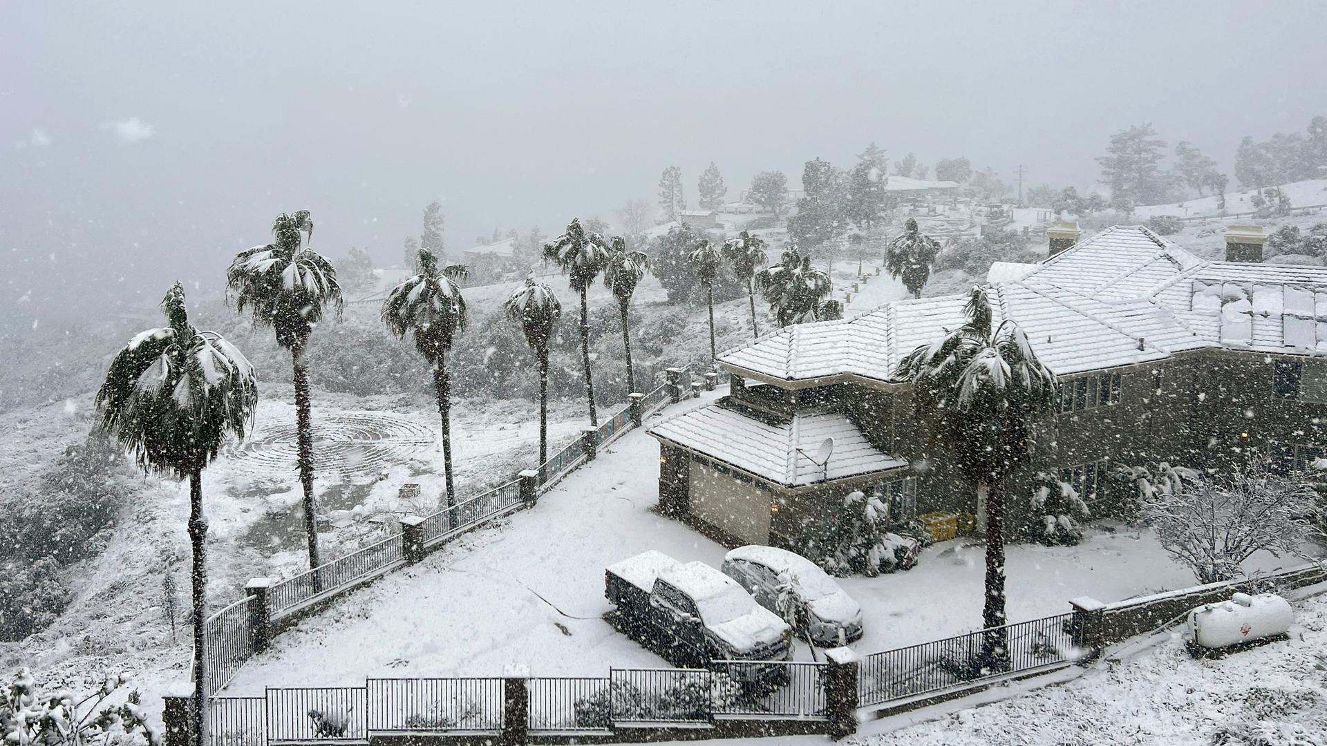 Schnee liegt auf einem Haus in Rancho Cucamonga, Kalifornien. Auch die Autos und Palmen sind von Schnee bedeckt.